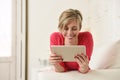 Young beautiful happy 30s woman smiling using digital tablet pad at home living room couch Royalty Free Stock Photo