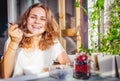 Young beautiful happy smiling woman eating yogurt and fresh berries at breakfast at home Royalty Free Stock Photo