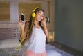 Young beautiful and happy student woman Asian Latin ethnicity mixed listening to music with headphones in bed singing and dancing Royalty Free Stock Photo