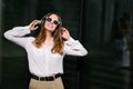 Young happy woman listens to music in white wireless headphones while walking around the city on a sunny day. Royalty Free Stock Photo