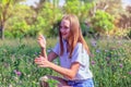 Young beautiful happy teenage girl sitting on a meadow among flowering plants and holding a ladybug in her hands, female portrait Royalty Free Stock Photo