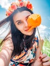 Young beautiful happy woman in flower wreath inhales the aroma of a poppy flower and make selfie on nature background Royalty Free Stock Photo