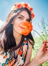 Young beautiful happy woman in flower wreath inhales the aroma of a poppy flower. Pretty woman with a red poppy flower Royalty Free Stock Photo