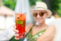 Young beautiful happy woman holding in hand and give glass with fresh cold strawberry non-alcoholic mojito cocktail Royalty Free Stock Photo