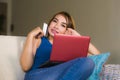 Young beautiful and happy woman at home living room holding credit card using laptop computer for banking and online shopping smil Royalty Free Stock Photo