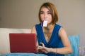 Young beautiful and happy woman at home living room holding credit card using laptop computer for banking and online shopping smil Royalty Free Stock Photo