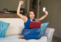 Young beautiful and happy woman at home living room holding credit card using laptop computer for banking and online shopping smil Royalty Free Stock Photo