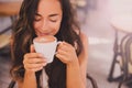 Young beautiful happy woman enjoying cappuccino in a cafe