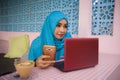 Young beautiful and happy woman in muslim hijab head scarf working with laptop computer and mobile phone networking running inter Royalty Free Stock Photo