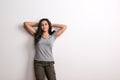 Young beautiful happy woman standing in a studio in studio, hands behind her head. Royalty Free Stock Photo