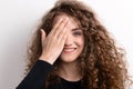 Young beautiful happy woman in studio, covering her eye. Royalty Free Stock Photo