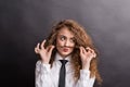 Young woman in studio, wearing white shirt and black tie, making fake mustaches. Royalty Free Stock Photo