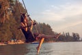 Young beautiful happy woman swinging on a swing on the beach during sunset, relaxing travel lifestyle concept Royalty Free Stock Photo