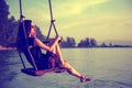 Young beautiful happy woman swinging on a swing on the beach during sunset, relaxing travel lifestyle concept Royalty Free Stock Photo