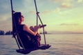 Young beautiful happy woman swinging on a swing on the beach during sunset, relaxing travel lifestyle concept Royalty Free Stock Photo