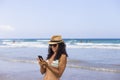 Young beautiful happy woman using her mobile phone at the beach. Sea and clear blue sky background. Summer. Lifestyle Royalty Free Stock Photo