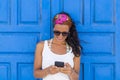 Young beautiful happy woman using her mobile phone over a blue door background. Summer. Lifestyle Royalty Free Stock Photo