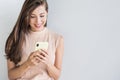 Young beautiful happy woman using smart phone. Girl texting on her mobile phone. Isolated on grey background Royalty Free Stock Photo