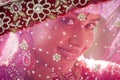 Young beautiful Hindu bride looking through jeweled veil