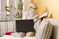 Young beautiful hipster woman reading a book while holding computer