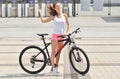 Young beautiful hipster woman in white dress and pink shorts, summer trend style, riding bicycle, travel Royalty Free Stock Photo