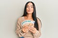 Young beautiful hispanic girl holding bunch of 50 euro banknotes looking at the camera blowing a kiss being lovely and sexy