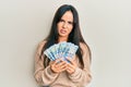 Young beautiful hispanic girl holding south african 100 rand banknotes in shock face, looking skeptical and sarcastic, surprised Royalty Free Stock Photo