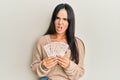 Young beautiful hispanic girl holding 10 united kingdom pounds banknotes in shock face, looking skeptical and sarcastic, surprised