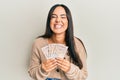 Young beautiful hispanic girl holding 10 united kingdom pounds banknotes smiling and laughing hard out loud because funny crazy