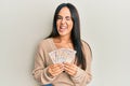Young beautiful hispanic girl holding 10 united kingdom pounds banknotes winking looking at the camera with sexy expression,