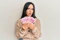 Young beautiful hispanic girl holding yuan chinese banknotes in shock face, looking skeptical and sarcastic, surprised with open Royalty Free Stock Photo