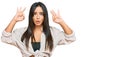 Young beautiful hispanic girl wearing casual clothes looking surprised and shocked doing ok approval symbol with fingers Royalty Free Stock Photo