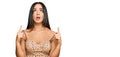 Young beautiful hispanic girl wearing sexy party dress amazed and surprised looking up and pointing with fingers and raised arms Royalty Free Stock Photo