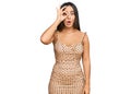 Young beautiful hispanic girl wearing sexy party dress doing ok gesture shocked with surprised face, eye looking through fingers Royalty Free Stock Photo