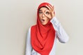 Young beautiful hispanic girl wearing traditional islamic hijab scarf doing ok gesture shocked with surprised face, eye looking Royalty Free Stock Photo