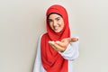 Young beautiful hispanic girl wearing traditional islamic hijab scarf smiling friendly offering handshake as greeting and