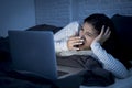 Young beautiful hispanic internet addict woman on bed with computer laptop yawning tired Royalty Free Stock Photo