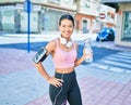 Young beautiful hispanic sport woman wearing runner outfit and headphones, drinking fresh water from the bottle Royalty Free Stock Photo