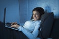 Young beautiful hispanic woman on bed at home laughing happy on laptop computer at night Royalty Free Stock Photo