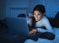 Young beautiful hispanic woman on bed at home laughing happy on laptop computer at night Royalty Free Stock Photo