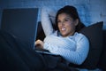 Young beautiful hispanic woman on bed at home working happy on laptop computer at night Royalty Free Stock Photo