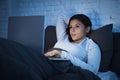 Young beautiful hispanic woman on bed at home working relaxed on laptop computer at night