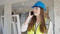 Young beautiful hispanic woman builder smiling confident talking on smartphone at construction site Royalty Free Stock Photo