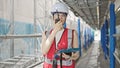 Young beautiful hispanic woman builder talking on walkie talkie using touchpad at street Royalty Free Stock Photo