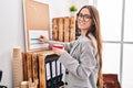 Young beautiful hispanic woman business worker drinking coffee writing on cork board at office Royalty Free Stock Photo