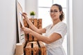 Young beautiful hispanic woman business worker hanging paperwork on cork board at office Royalty Free Stock Photo