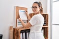Young beautiful hispanic woman business worker hanging paperwork on cork board at office Royalty Free Stock Photo
