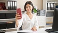Young beautiful hispanic woman business worker make selfie smartphone working at office Royalty Free Stock Photo