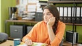 Young beautiful hispanic woman business worker sitting on table with serious face at office Royalty Free Stock Photo