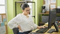 Young beautiful hispanic woman business worker sitting on the table suffering for backache at the office Royalty Free Stock Photo